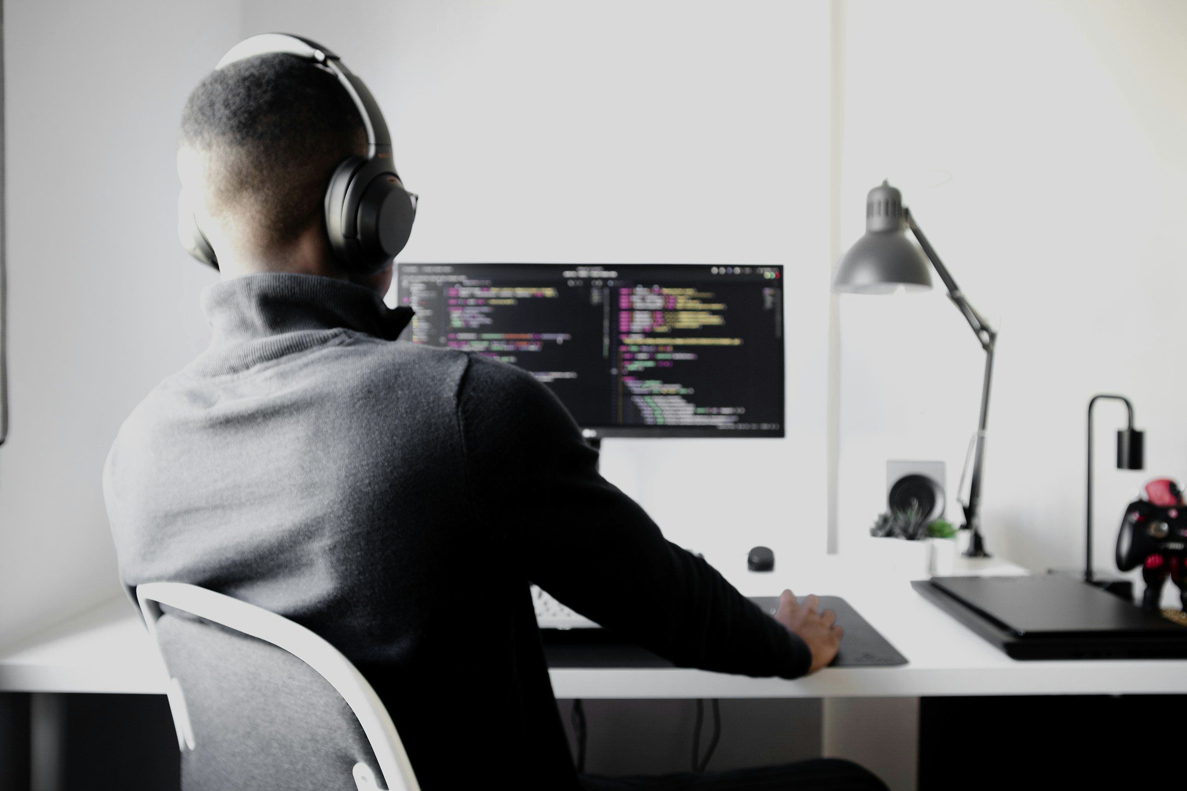 Developer with headphones in front of a screen with source code